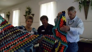Ellen Whitley, J.D. Todd, and Mark Whitley look at the prayer shawls Todd made for them
